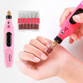 Eine Person verwendet das Fashiongirl Electric Nail File 6-in-1 Manicure Set in Pink für ihre Fingernägel, wobei die mitgelieferten Bohrer und Schleifbänder neben dem Werkzeug zu sehen sind.