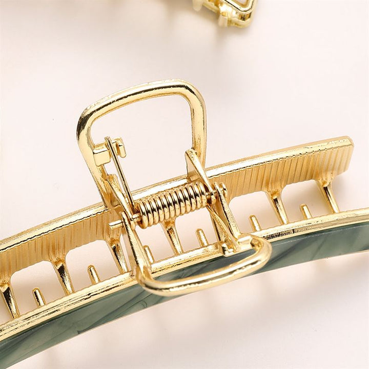 Close-up of the SOHO Abby Hair Claw - Ginger by SOHO, featuring a gold metal finish with a green accent on the lower edge and spring hinge, designed for everyday use to securely hold hair in place.