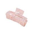 Die SOHO Aria Hair Claw – Blush ist eine durchscheinende, rosa, rechteckige Acetat-Haarspange mit ineinandergreifenden Zähnen und einem geschwungenen Design, die vor einem weißen Hintergrund abgebildet ist.