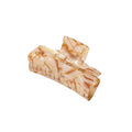 Die SOHO Aria Hair Claw – Champagne von SOHO hat ein rechteckiges Design mit abgerundeten Kanten aus beige- und hellbraun marmoriertem Acetat und ist ein schickes Haaraccessoire, das auf weißem Hintergrund präsentiert wird.
