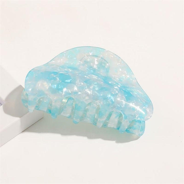 The SOHO Cleo Hair Claw in Crystal Blue features a large, translucent blue and white marble pattern with wide teeth, displayed on a white surface.