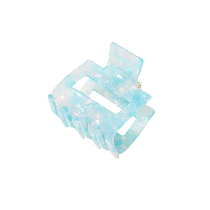 Die SOHO Ema Hair Claw in Crystal Blue zeichnet sich durch ein halbtransparentes, marmoriertes hellblaues Design mit rechteckigem Ausschnitt und ineinandergreifenden Zähnen aus – ideal, um jeder eleganten Frisur einen schicken, mühelosen Halt zu verleihen.