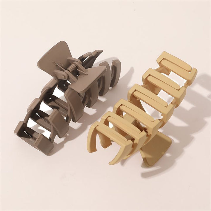 Two SOHO Just Hair Claws in brown, with interlocking teeth and sturdy springs, are open and side by side on a light surface. Stylish SOHO accessories for secure hair styling.
