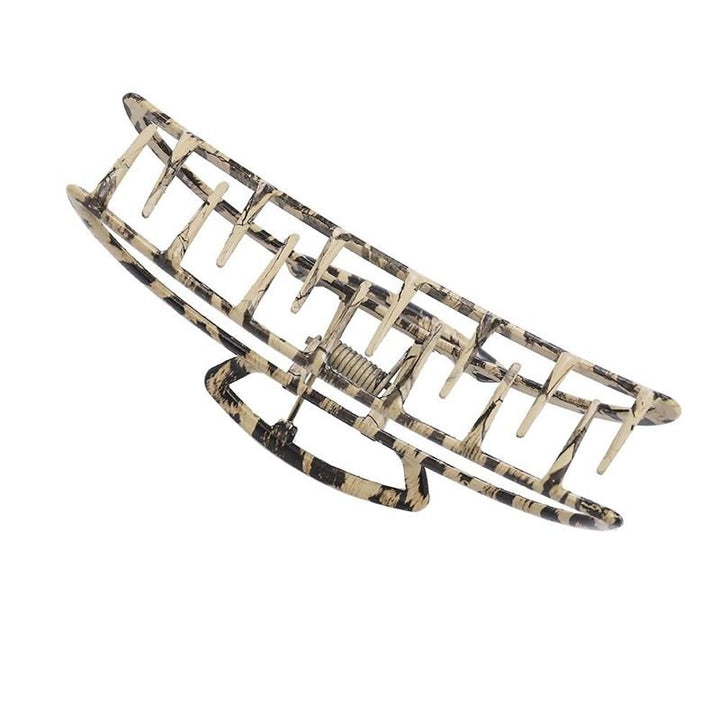 The SOHO Leopard Metal Barette Hair Claw by SOHO features a beige and black marbled design, interlocking teeth, and a rectangular open shape—a stylish accessory for secure hair styling.