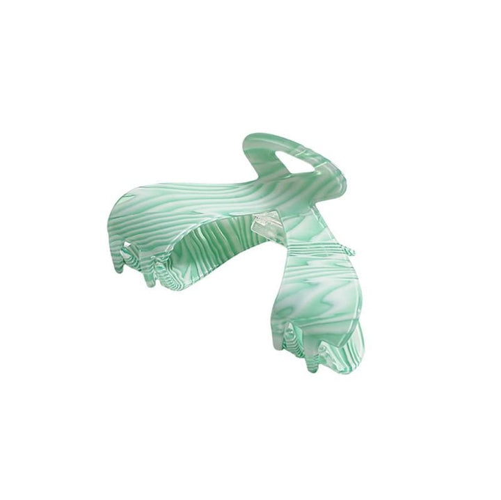 Die SOHO Malou Hair Claw – Green von SOHO zeichnet sich durch ein großes mintgrünes Marmormuster mit Wellenmuster und breiten, gebogenen Zinken aus, die vor einem weißen Hintergrund dargestellt sind.