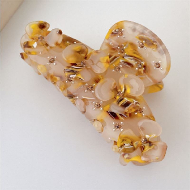 A close-up of the SOHO Posy Hair Claw - Cider by SOHO, showing its marbled beige, brown, and gold tones with embedded beads and a translucent glossy finish. This chic rhinestone hair clip is displayed on a white surface.