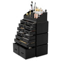Der UNIQ XXL Organizer mit 12 Schubladen und 16 Fächern in Schwarz bietet Platz für Kosmetika, Pinsel und Flaschen. Einige Schubladen sind leicht geöffnet und geben den Blick auf die darin aufbewahrten Make-up-Produkte frei.